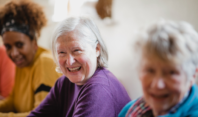 Older lady sat with two friends smiling