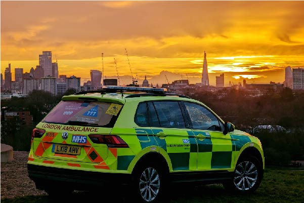 London ambulance car parked with the city skyline at sunset